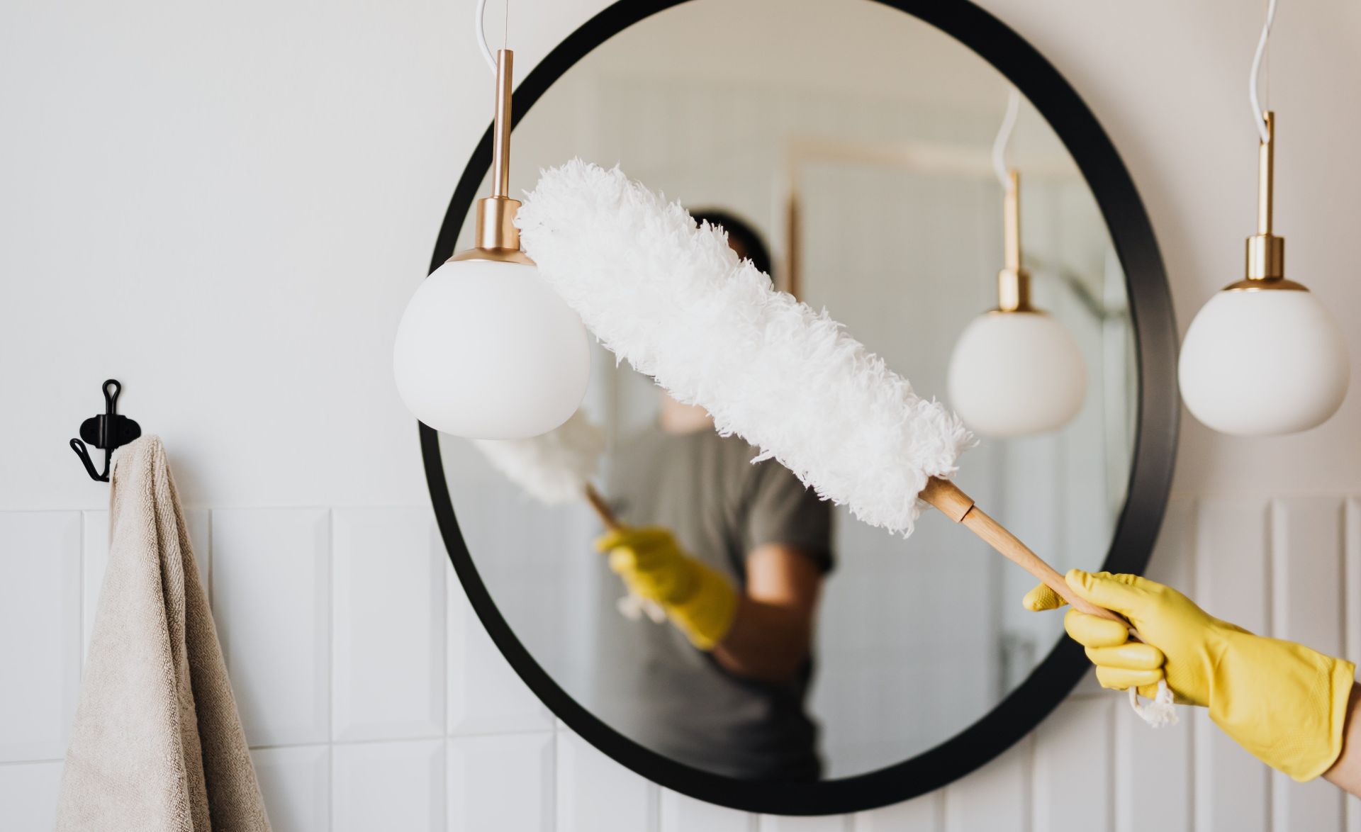 Crop woman dusting lamp during housework